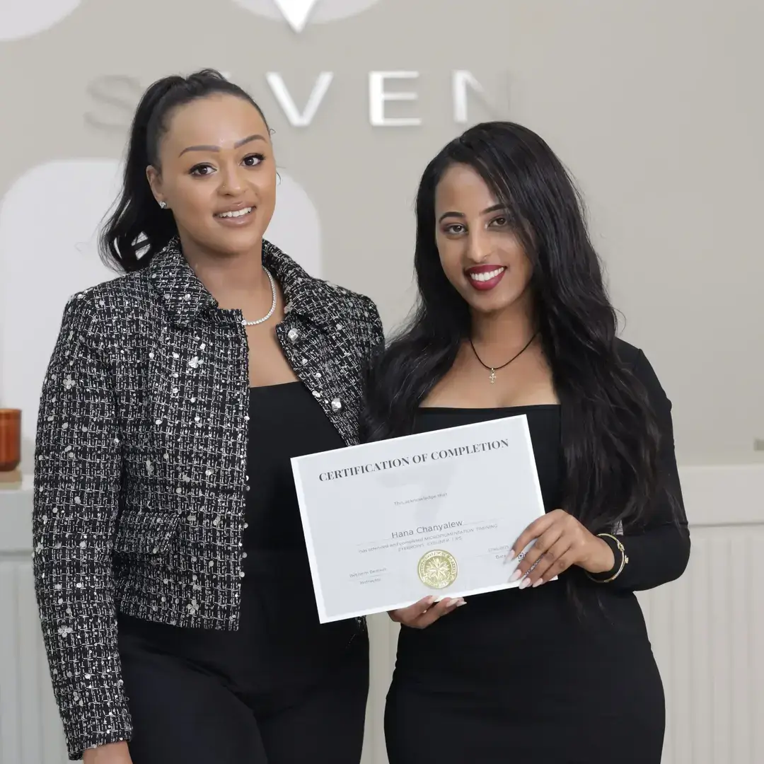 Permanent Makeup Certification at Seven Aesthetics: Teacher Betlehem Bereket with student Hana Chanyalew holding her certificate of completion after completing the course.